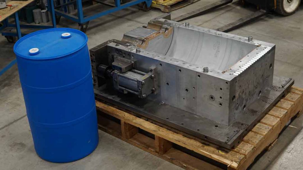 Industrial Plastic Drum next to extrusion blow mold.